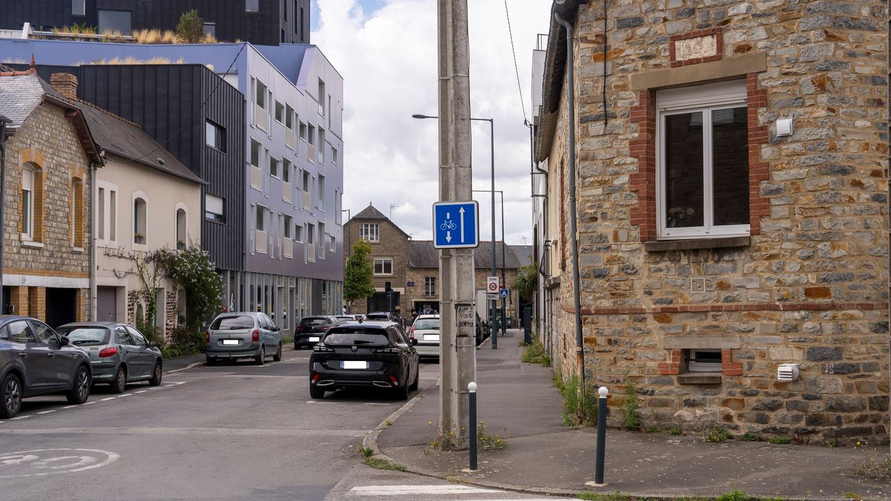 Panneau de signalisation à l'entrée d'une rue où des véhicules sont en stationnement.