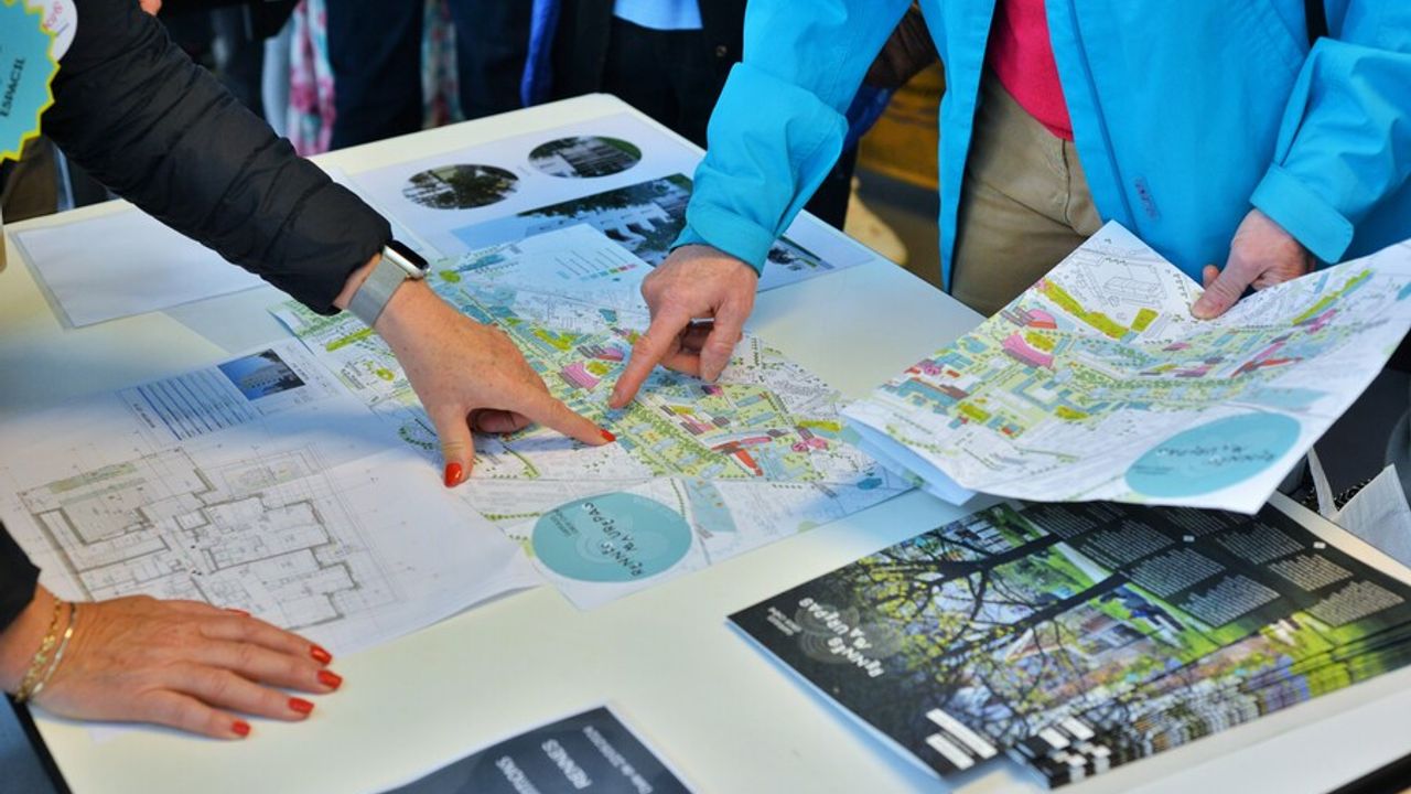 Deux personnes pointant du doigt des projets d’urbanisme sur une carte de la ville.