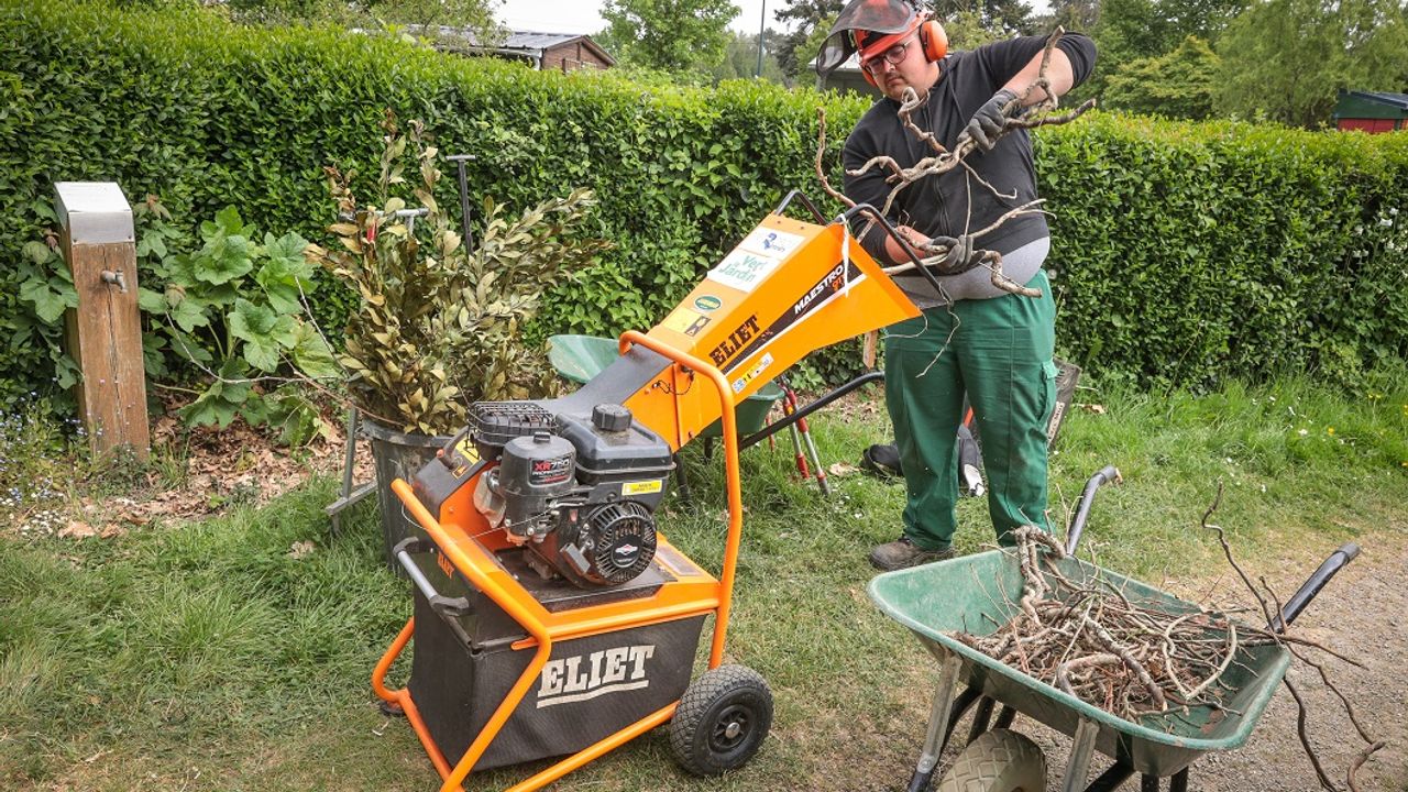 Travaux de jardins pour optimiser le zéro déchets. Un homme utilise une broyeuse pour réduire les tailles de haies.
