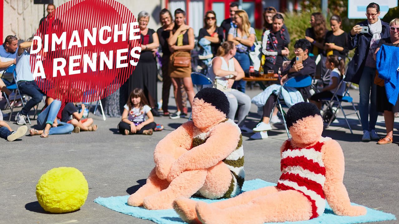 Au premier plan, deux baigneurs en peluche sur une serviette bleue. Au second plan, le public devant l'équipement culturel Le Triangle.