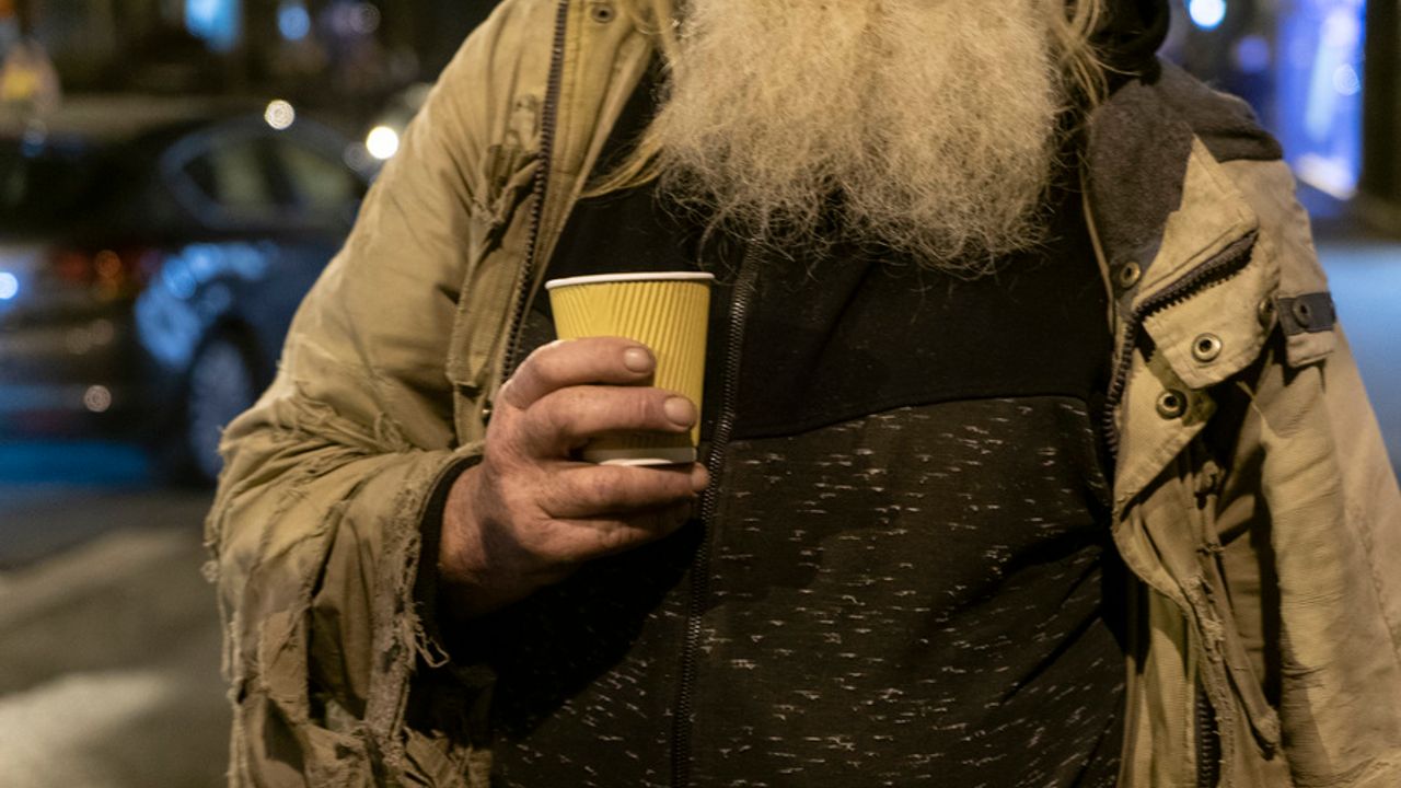 Personne sans-abri tenant un gobelet.