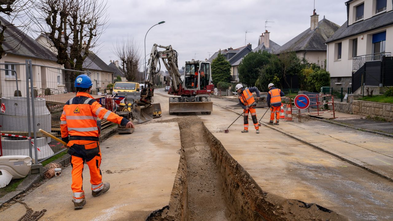 Engins de chantier et ouvriers qui remplacent une canalisation dans une rue.