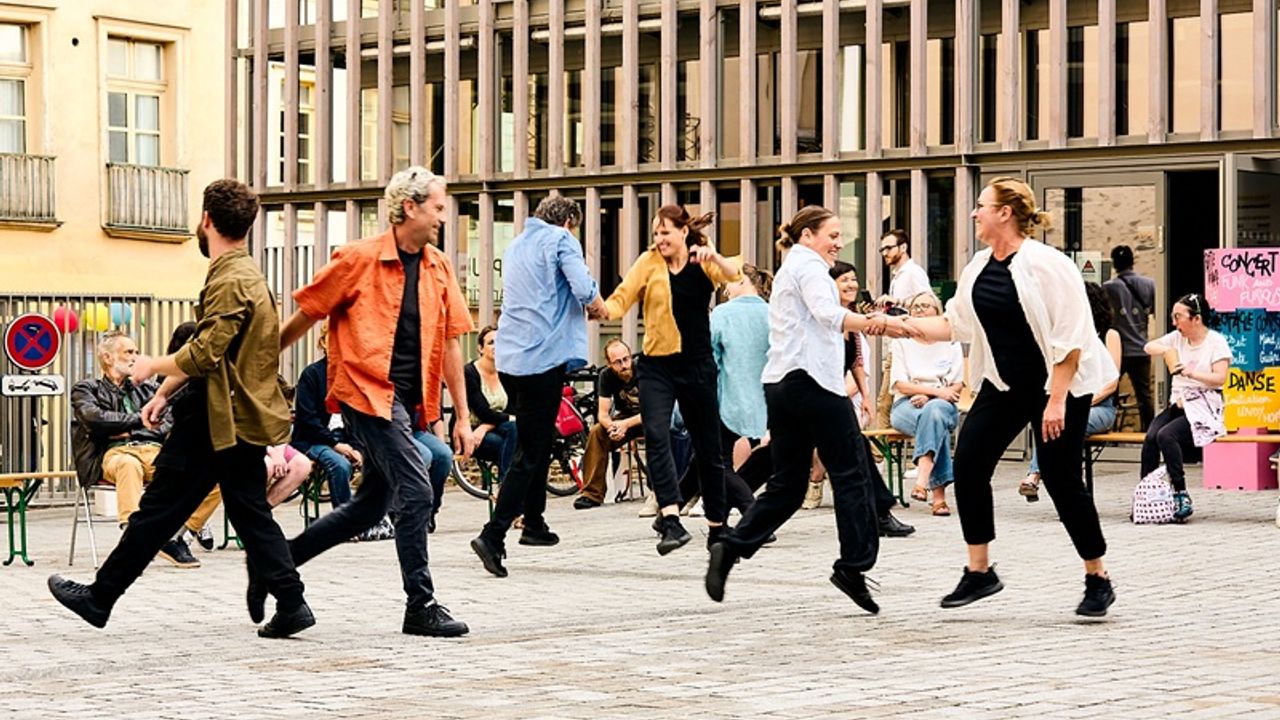 Des gens dansent sur une place publique. Ils ont l'air de prendre beaucoup de plaisir.