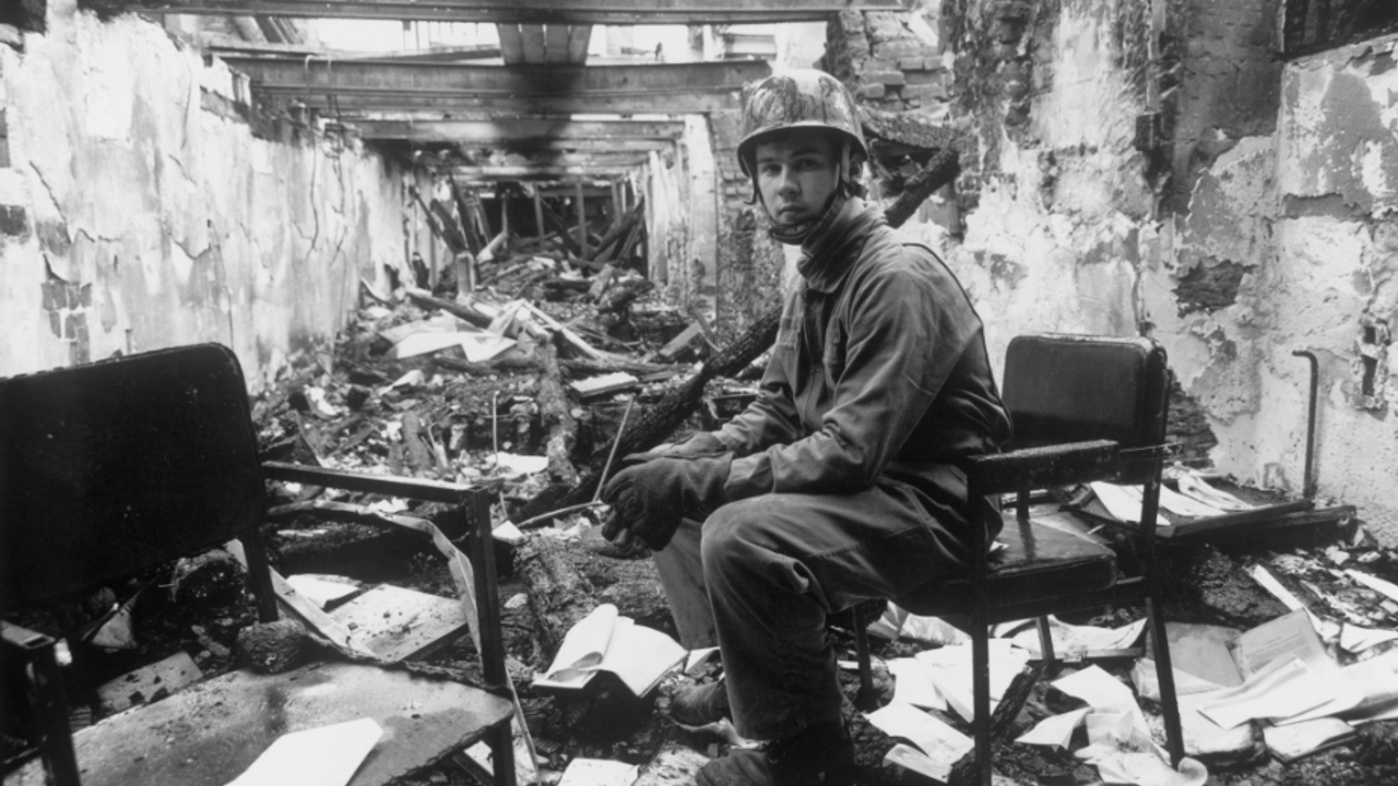 Un pompier est assis sur une chaise dans les décombres de l'incendie.