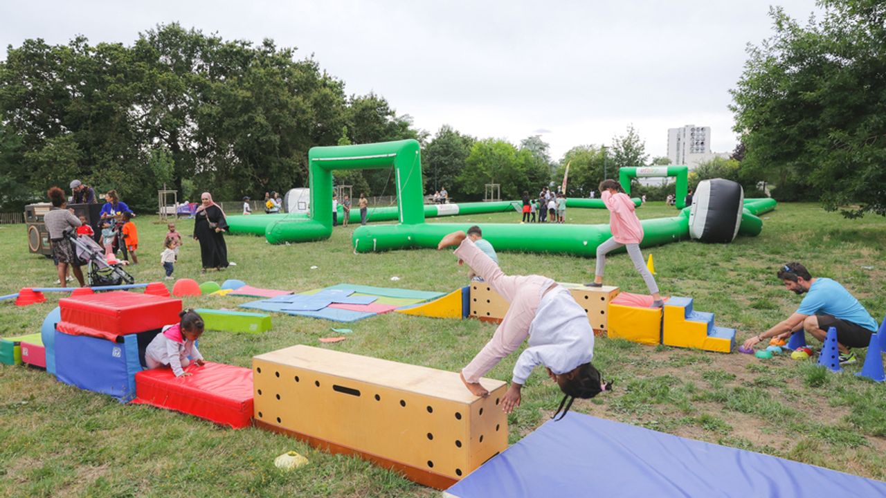 Caravane des sports dans le cadre de cet été à Rennes 2023 au square des Vickings dans le quartier Bréquigny à Rennes avec des enfants effectuant le parcours d'obstacles (avec des plots, tapis et escaliers en mousse, tunnel). En arrière plan il y a un terrain gonflable de foot.