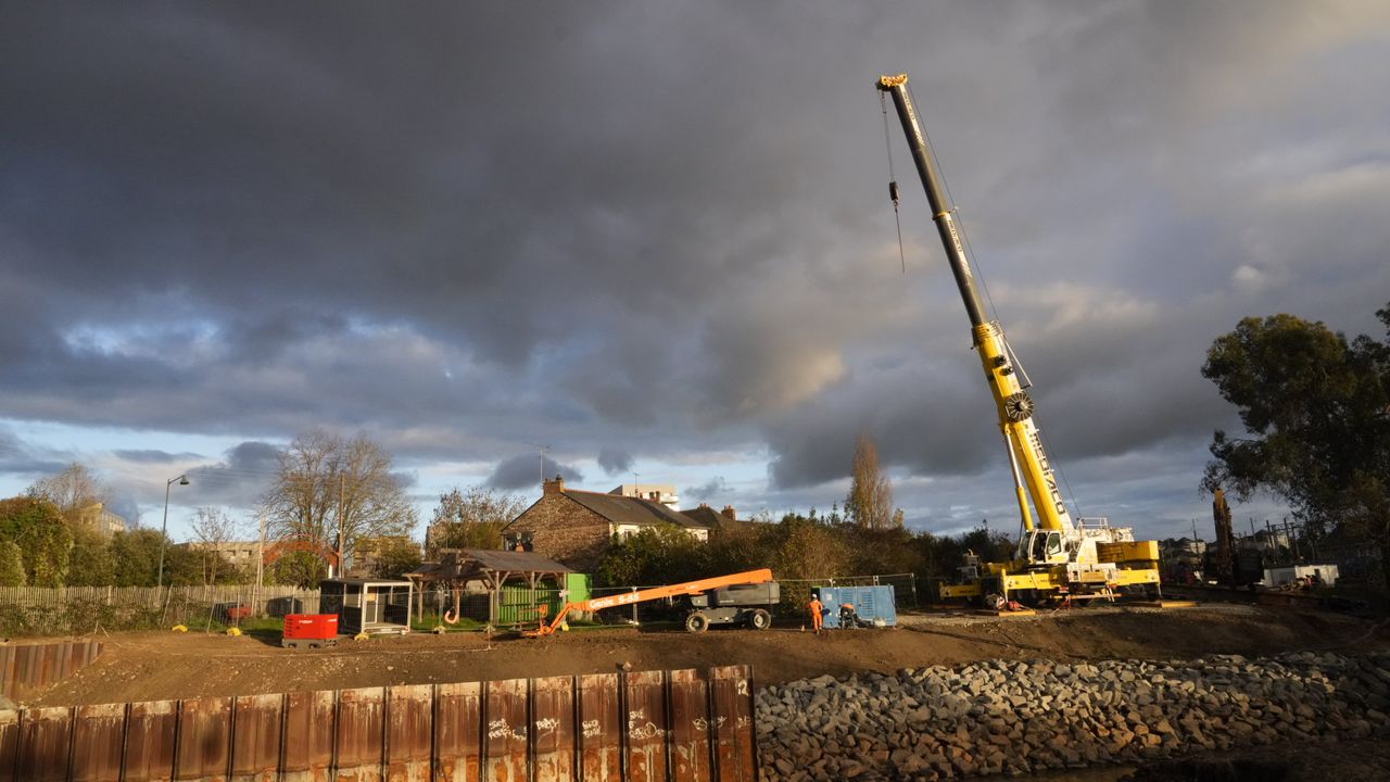 le mur de palplanches à moitié retiré au premier plan et une grue à l'arrière plan