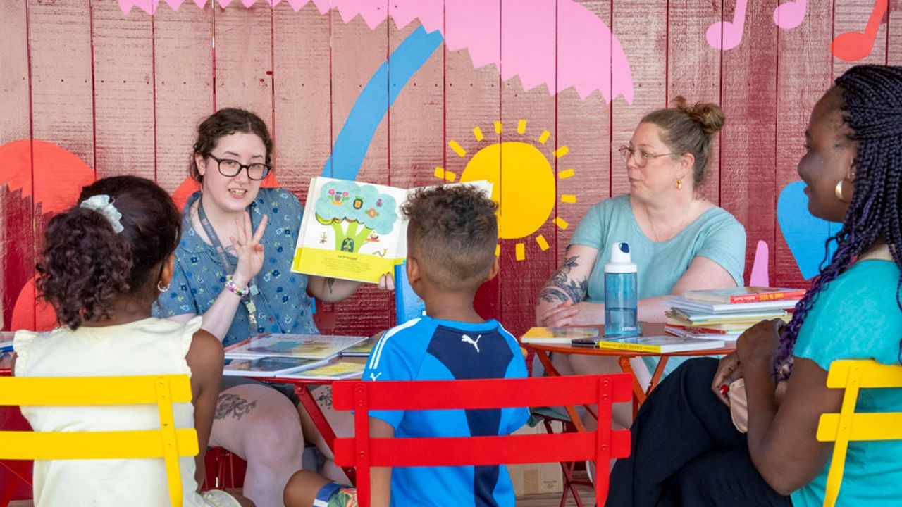 Des enfants écoutent une femme qui lit un livre