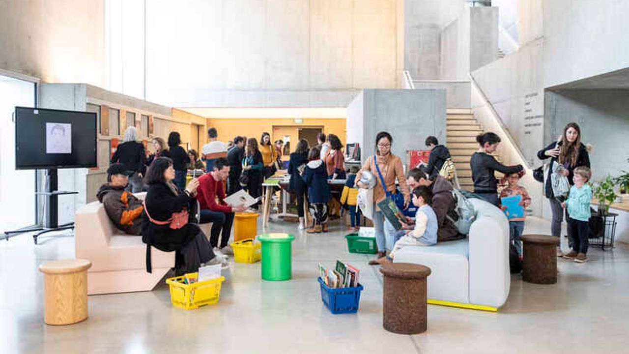 Dans le hall de l'Antipode un sol en béton accueille des visiteurs sur des canapés avec des bacs de lecture au sol