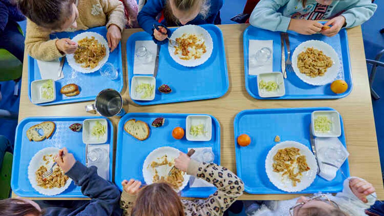 vue de haut de 6 enfants avec leurs plateaux repas à la cantine