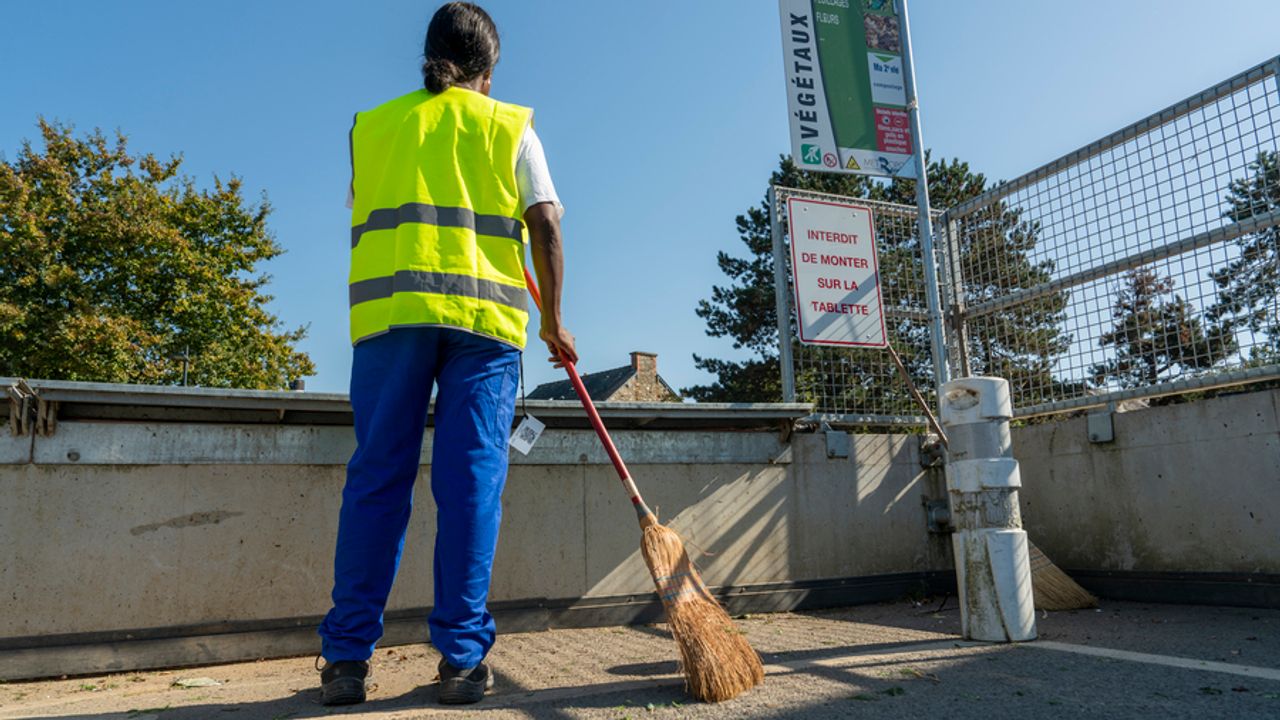 Une agente balaye le sol en déchèterie.