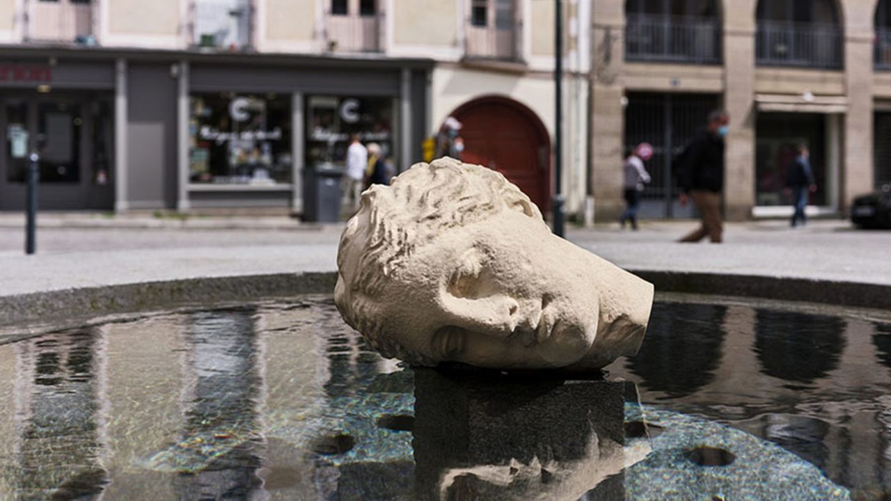 Sculpture de tête coupée, avec son reflet dans l’eau de la fontaine