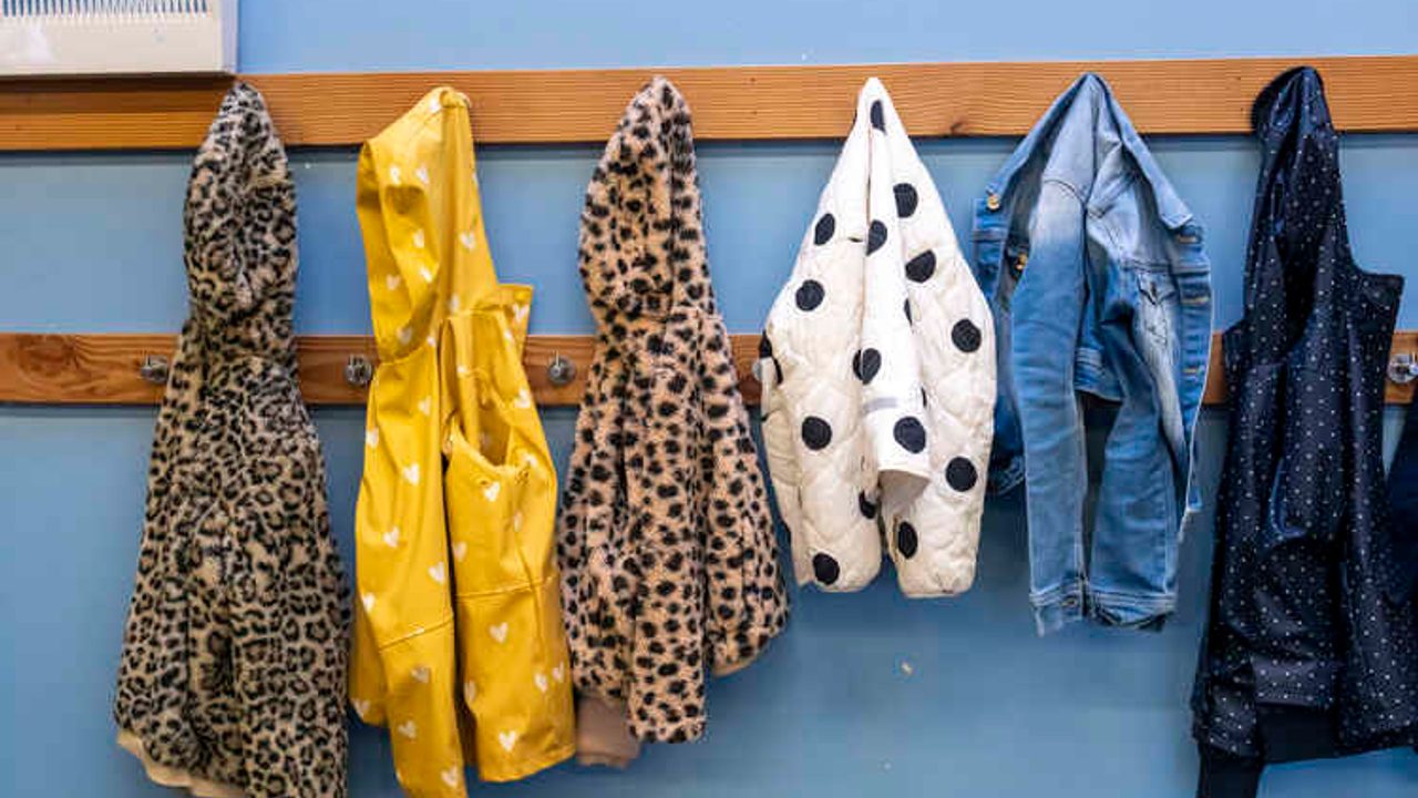 Des manteaux sont accrochés dans un couloir d'école. 