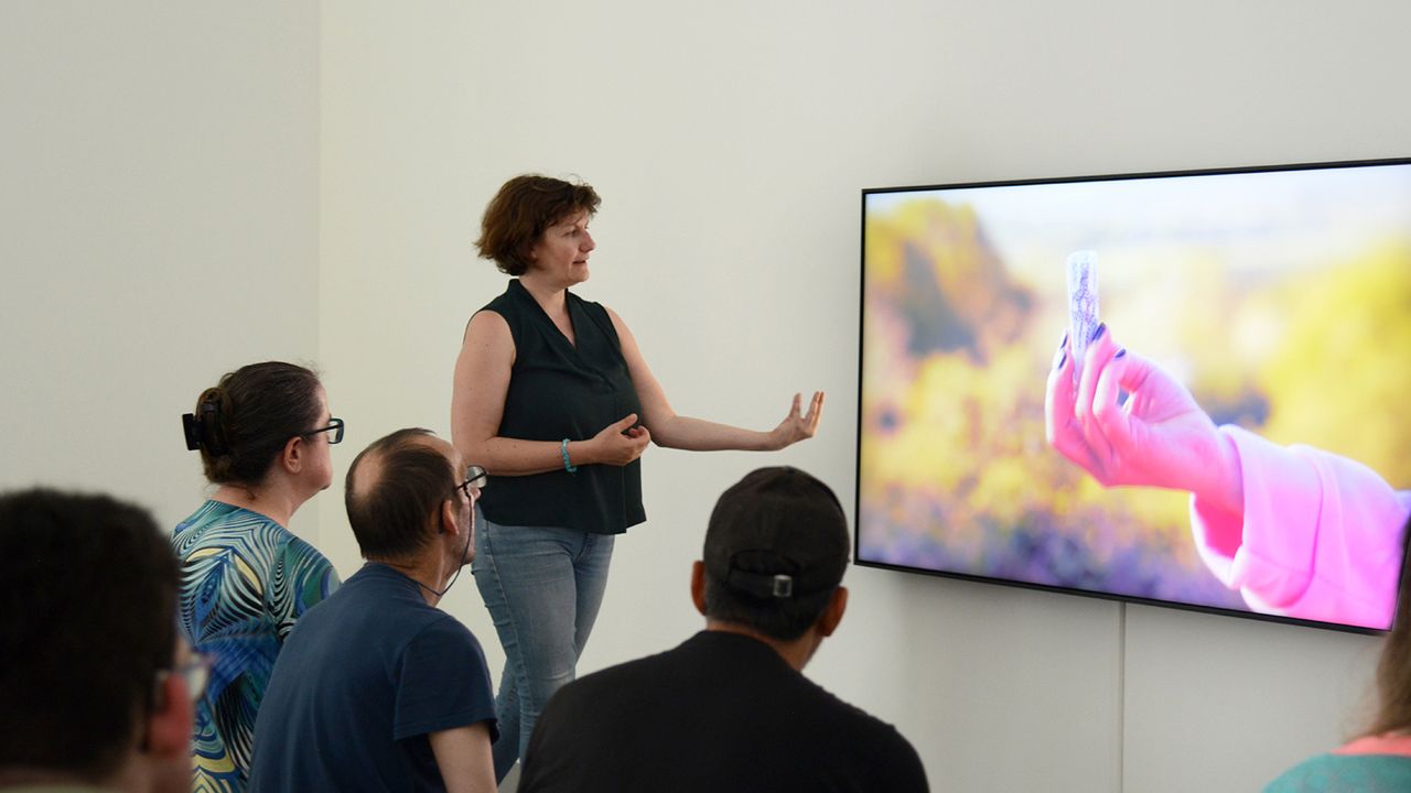 La médiatrice commente une vidéo-performance de l'artiste.