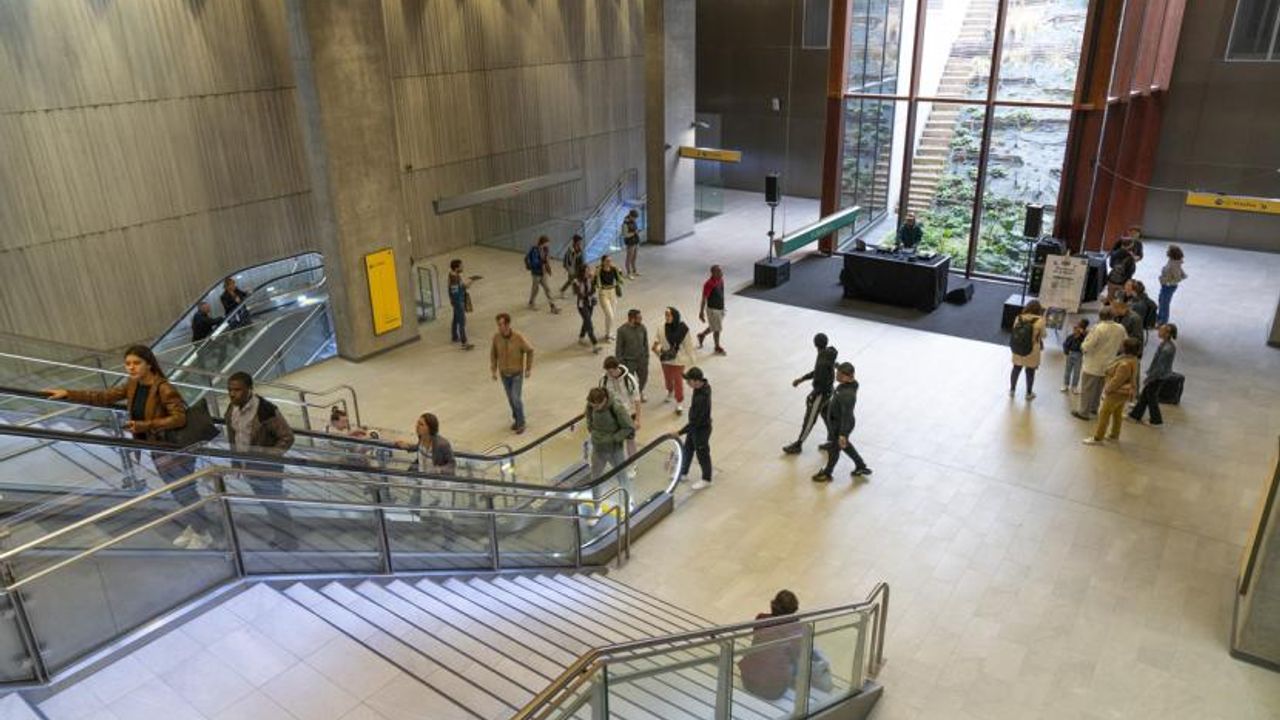 Des personnes circulent dans une station de la ligne b du métro de rennes. Au premier plan un escalier et un escalator.
