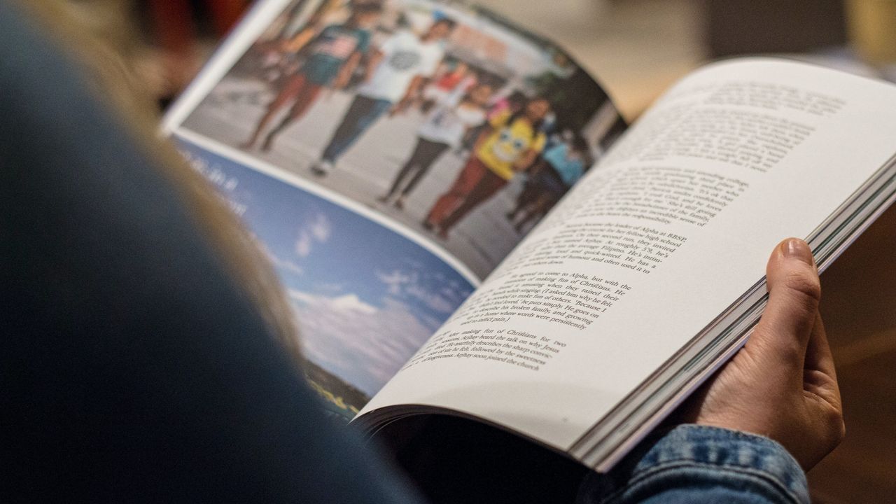 person in blue denim top reading book
