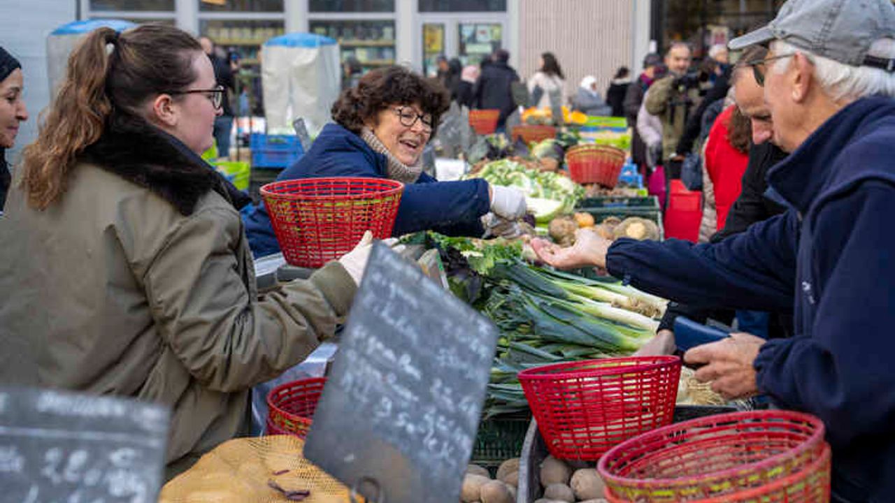 Une vendeuse rend la monnaie à un client sur un marché.
