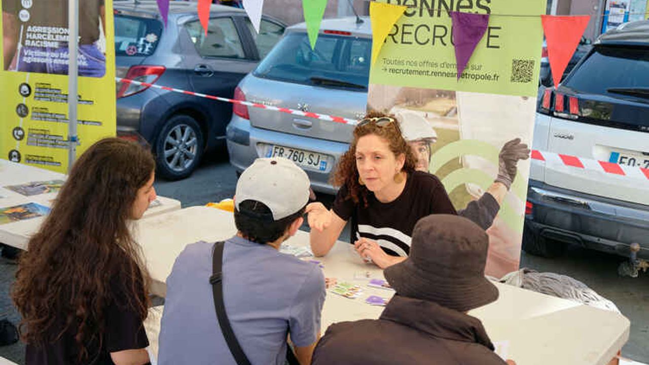 Trois jeunes face une femme à un bureau à l’extérieur, devant une affiche où il est écrit « Rennes recrute ».