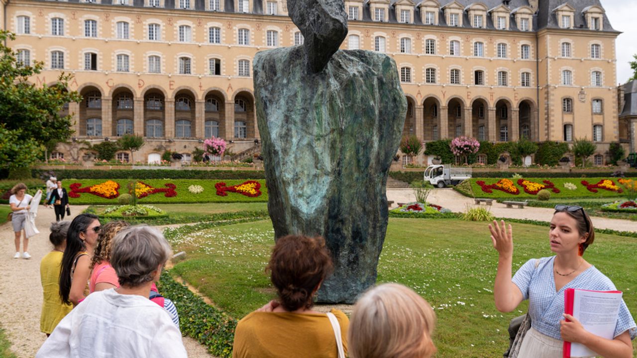 Photo d’une guide présentant une statue devant le Palais Saint-Georges.