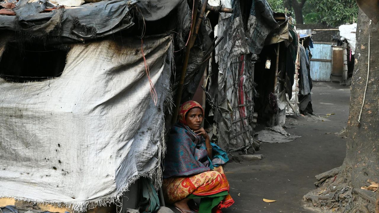 Person crouched outside a makeshift home