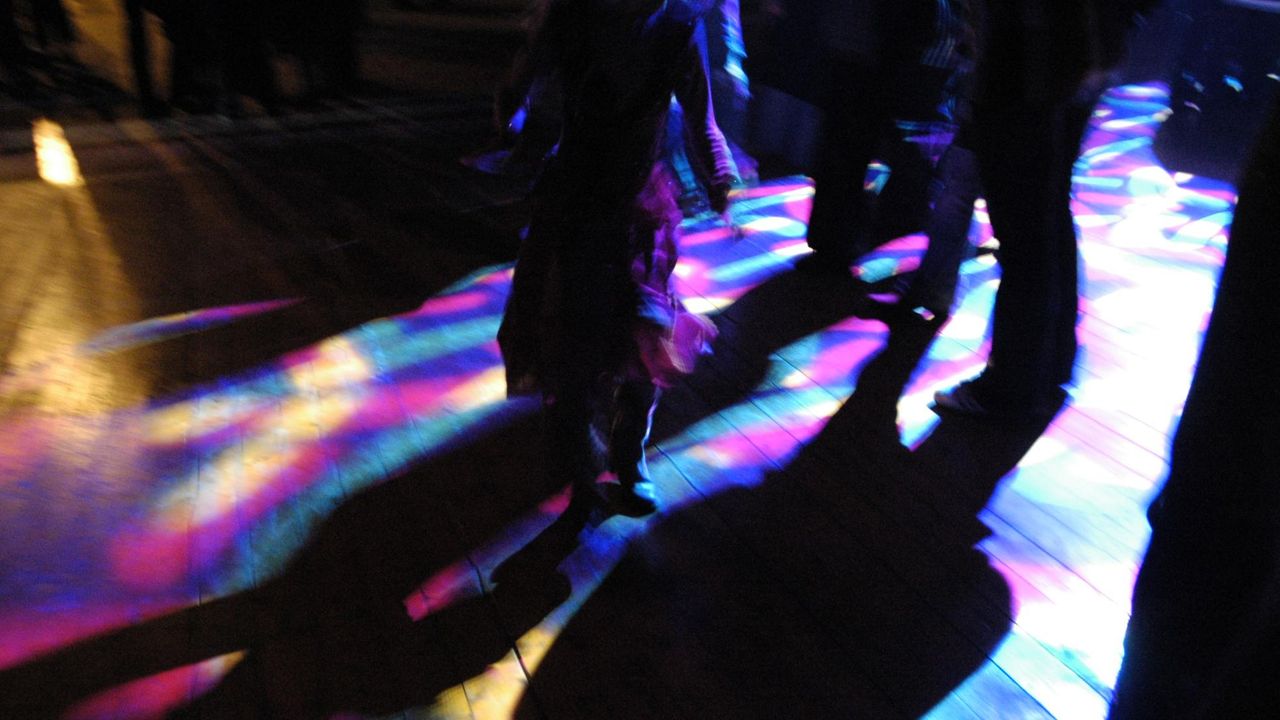 Des jambes et pieds s'agitent au rythme de la musique sur la piste éclairée par les lumières de différentes couleurs.