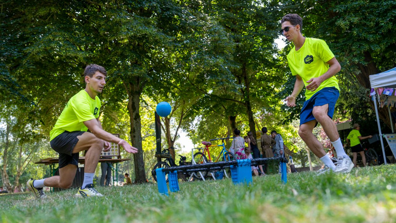 Sport en extérieur. Deux jeunes hommes au premier plan jouent au spikeball.