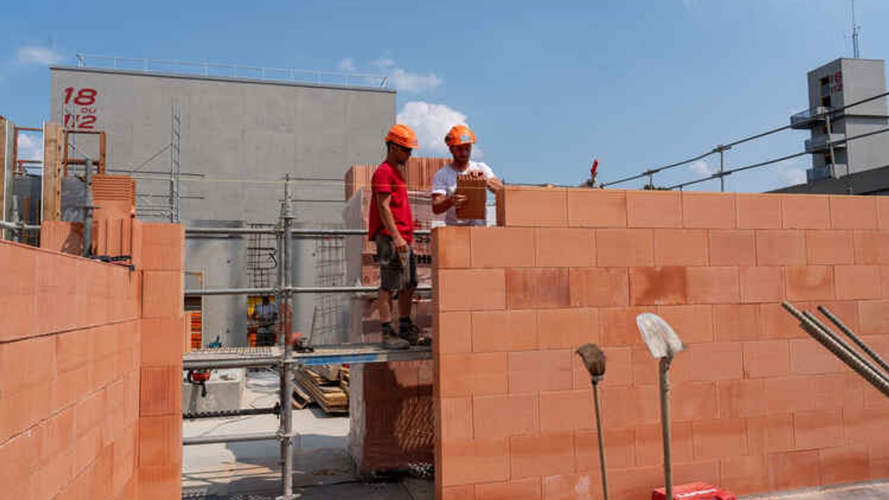 Des ouvriers sur un chantier de construction à Rennes. Au premier plan un mur de briques.