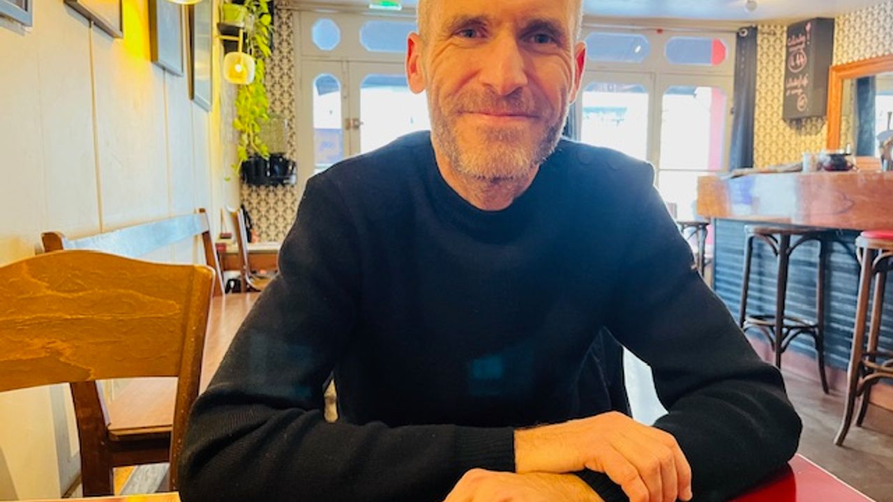 Melaine Dalibert en gros plan, assis à la table d'un café