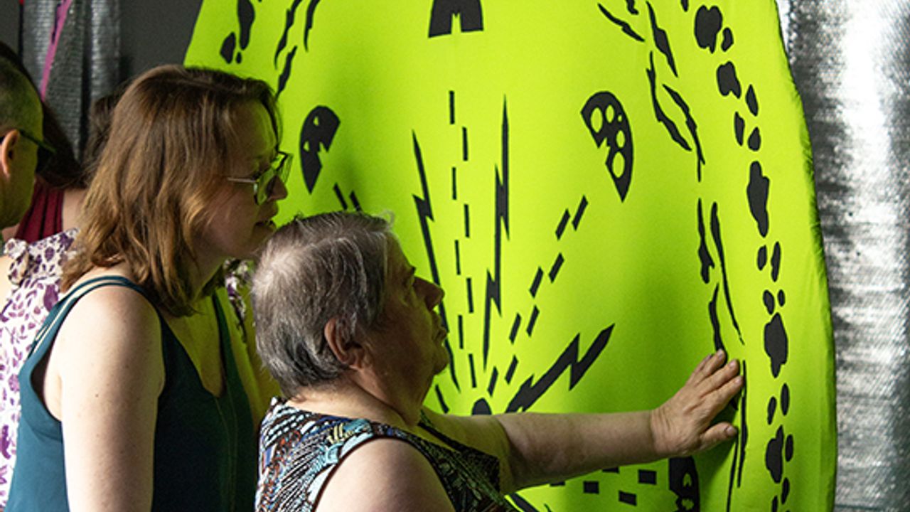 Une visiteuse touche du bout des doigts une œuvre.