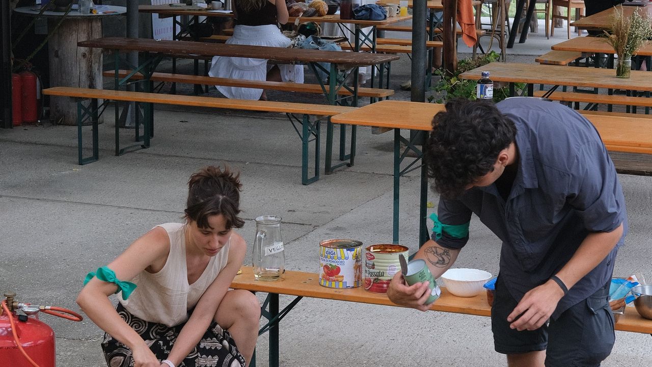 Two people cooking outside on massive pots