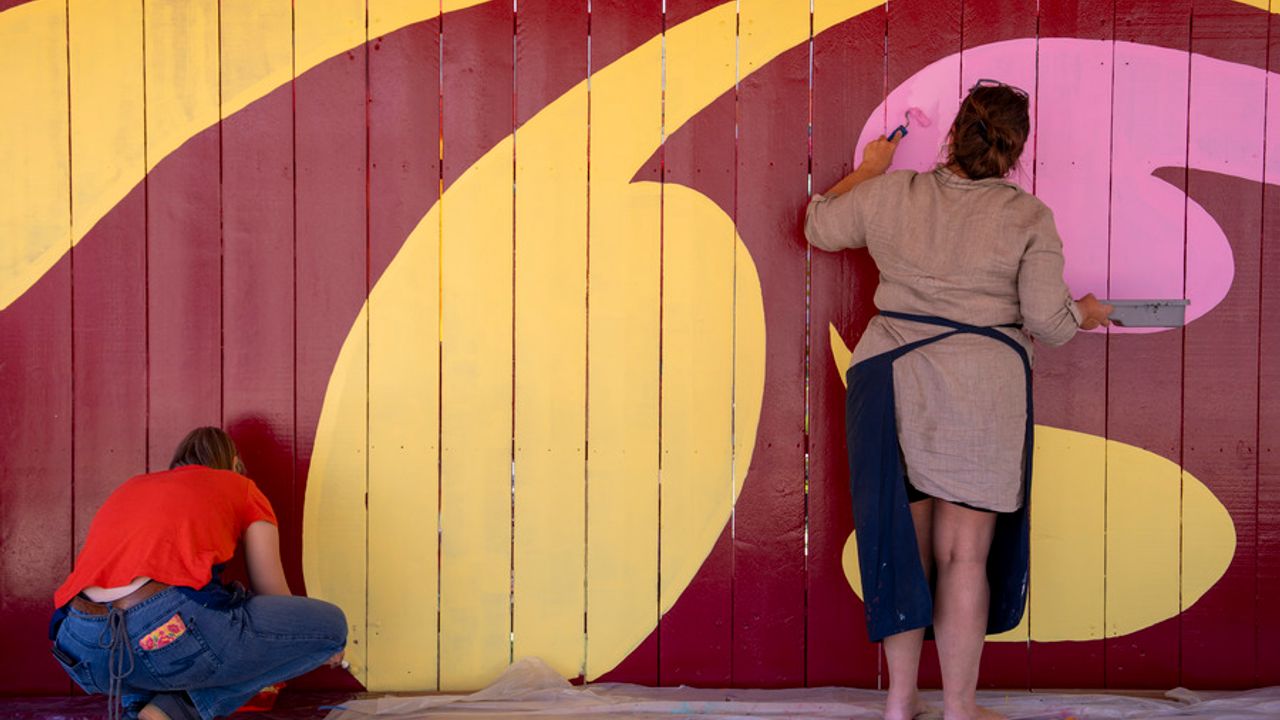 Des femmes en train de peindre la palissade du fond de scène