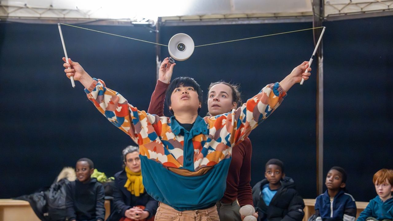 Deux artistes circassiennes manipulent un diabolo, devant des enfants