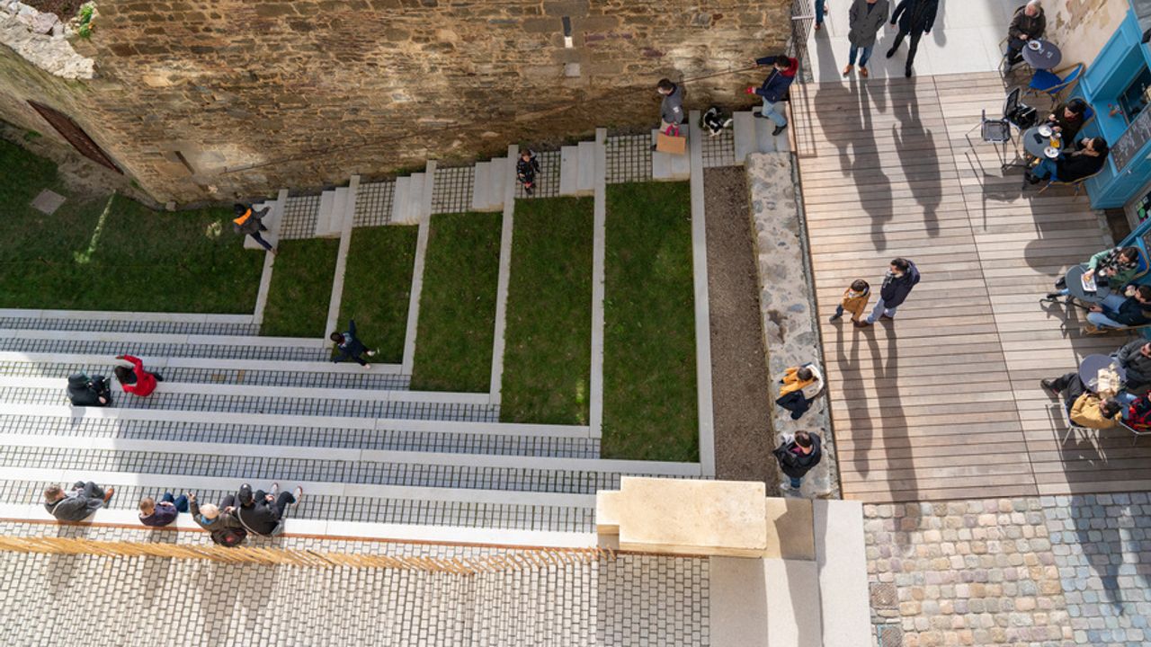 Des gens profitent des nouveaux escaliers en amphithéâtre, au pied de la porte mordelaise.