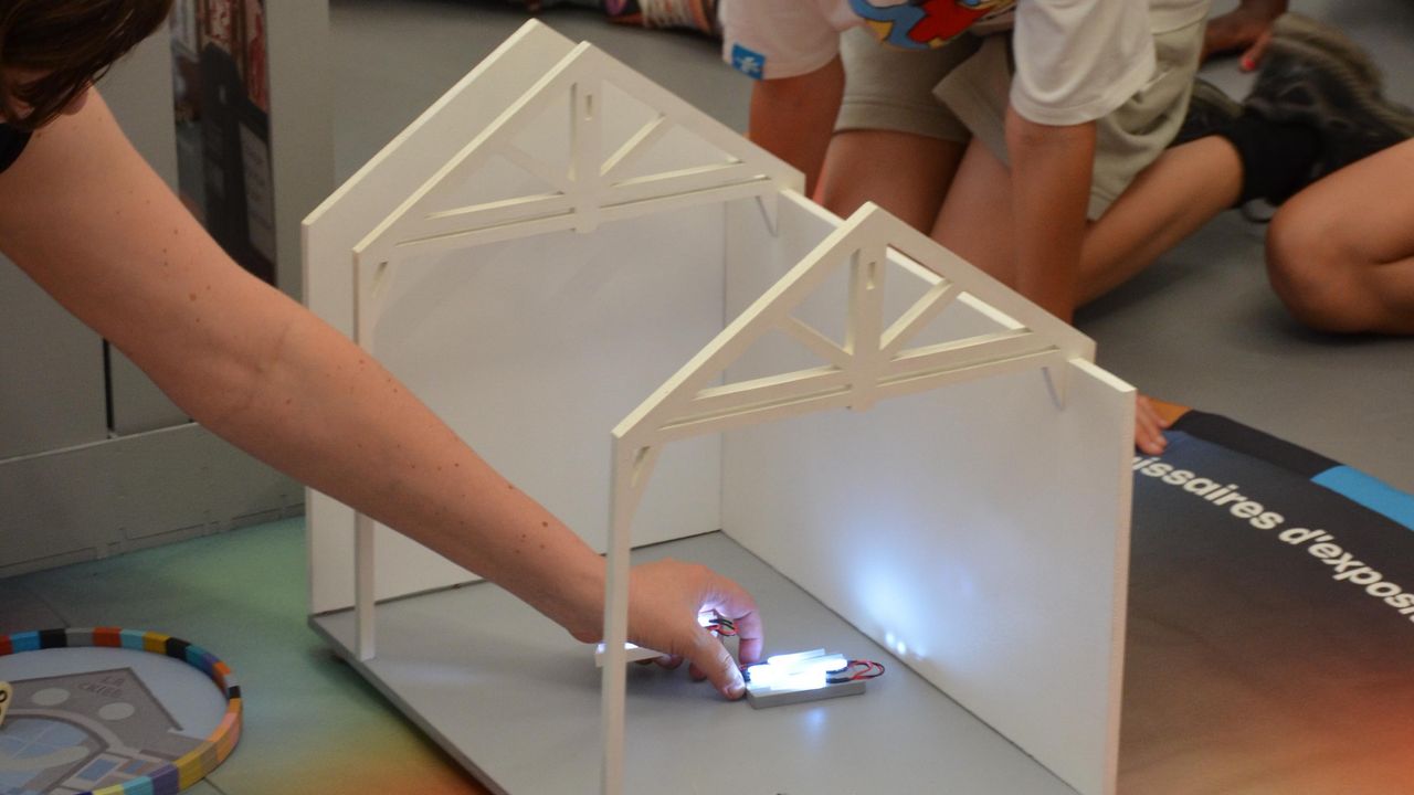 La médiatrice culturelle Amandine Braud place une oeuvre miniature dans l'espace d'exposition miniature du jeu collaboratif Rejouer La Criée, installé dans La Criée. 