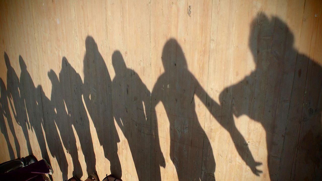 Des ombres de personnes dansant et se tenant par la main sont projetées sur un plancher.