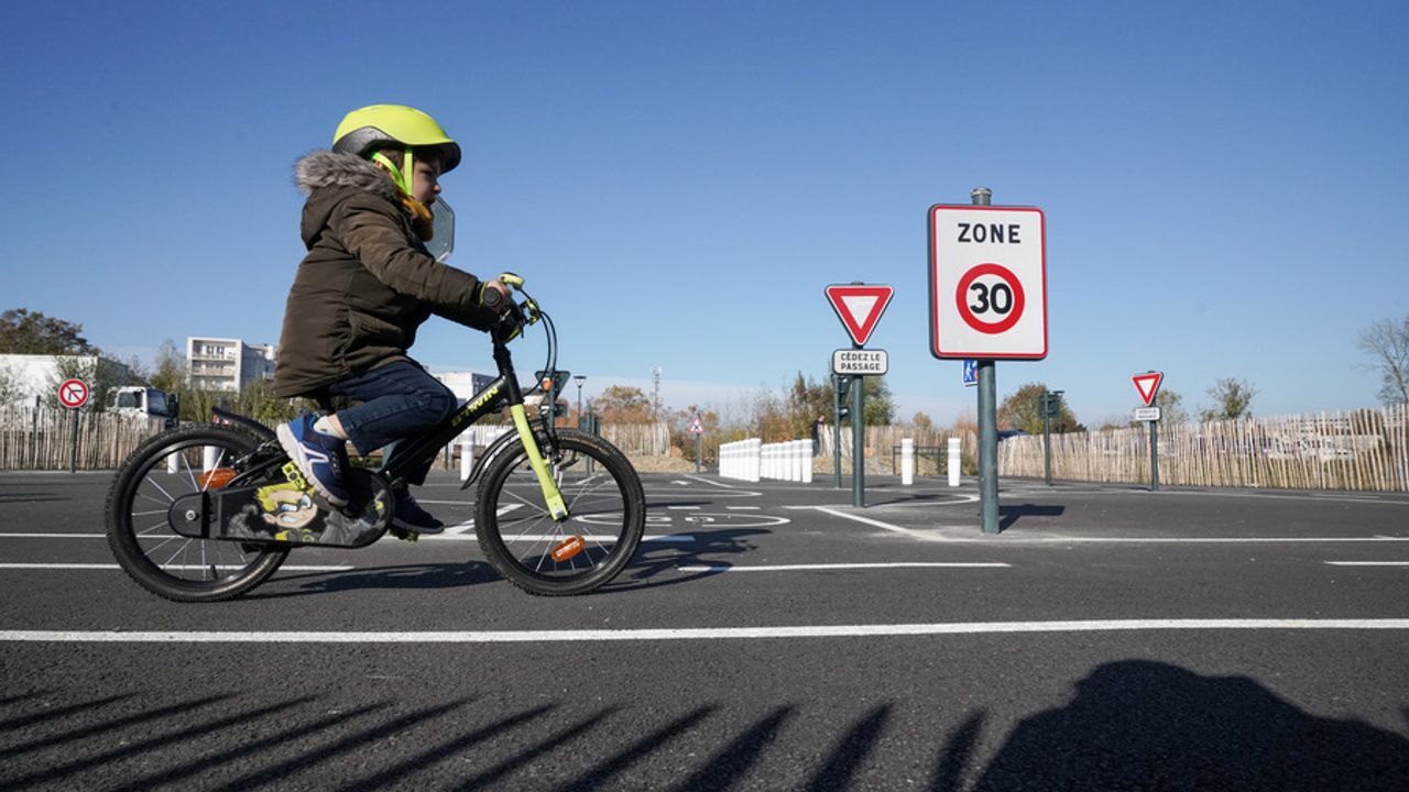 Un enfant fait du vélo sur un parcours d'apprentissage pour enfants (avec des panneaux plus petits) dans un quartier de Rennes