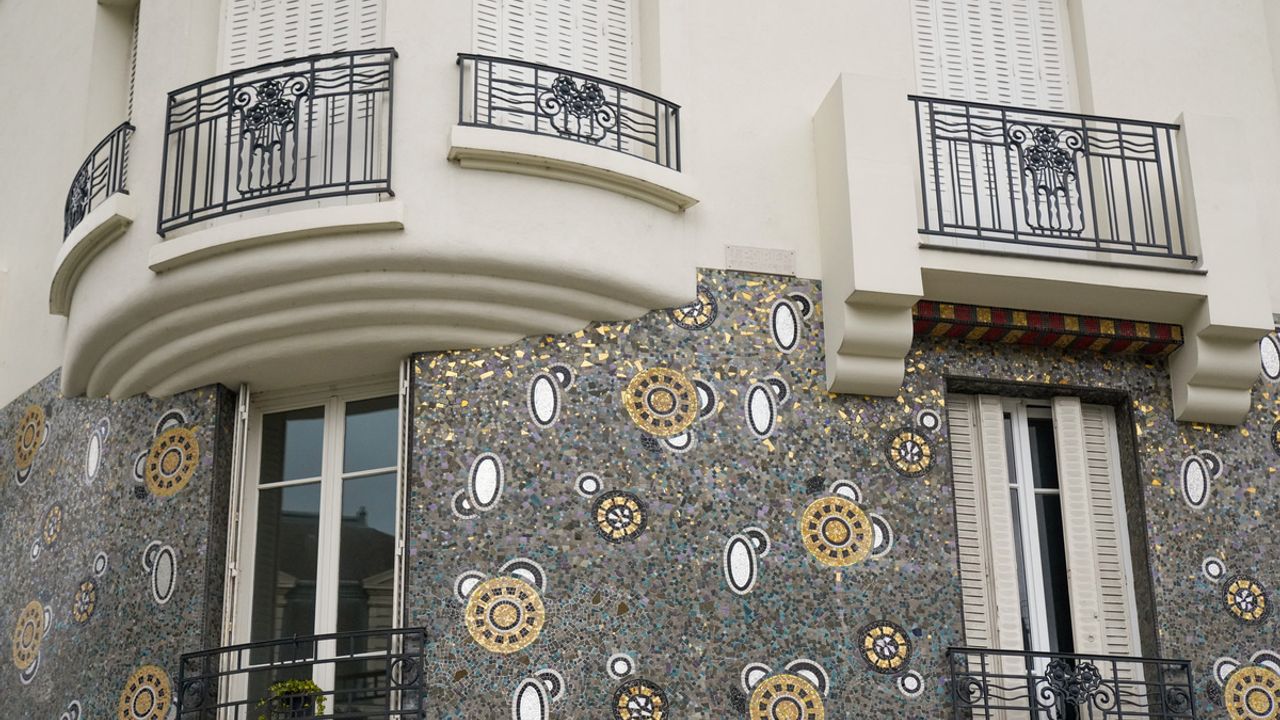 Détail de la façade de l'immeuble Poirier avec de nombreuses tesselles dorées qui ressortent sur un fond gris bleu foncé.