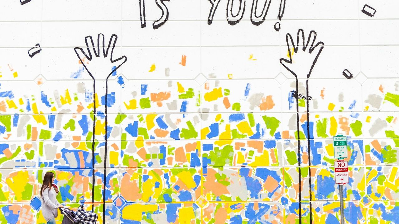 woman walking beside wall with the best gift is you graffiti