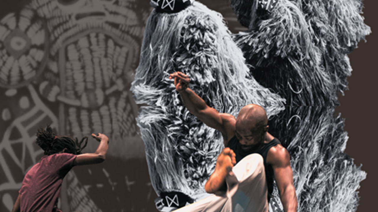 Vue de deux danseurs exécutant des figures acrobatiques dans un décor étrange, dont une sculpture avec de longs fils gris clair évoquant une créature