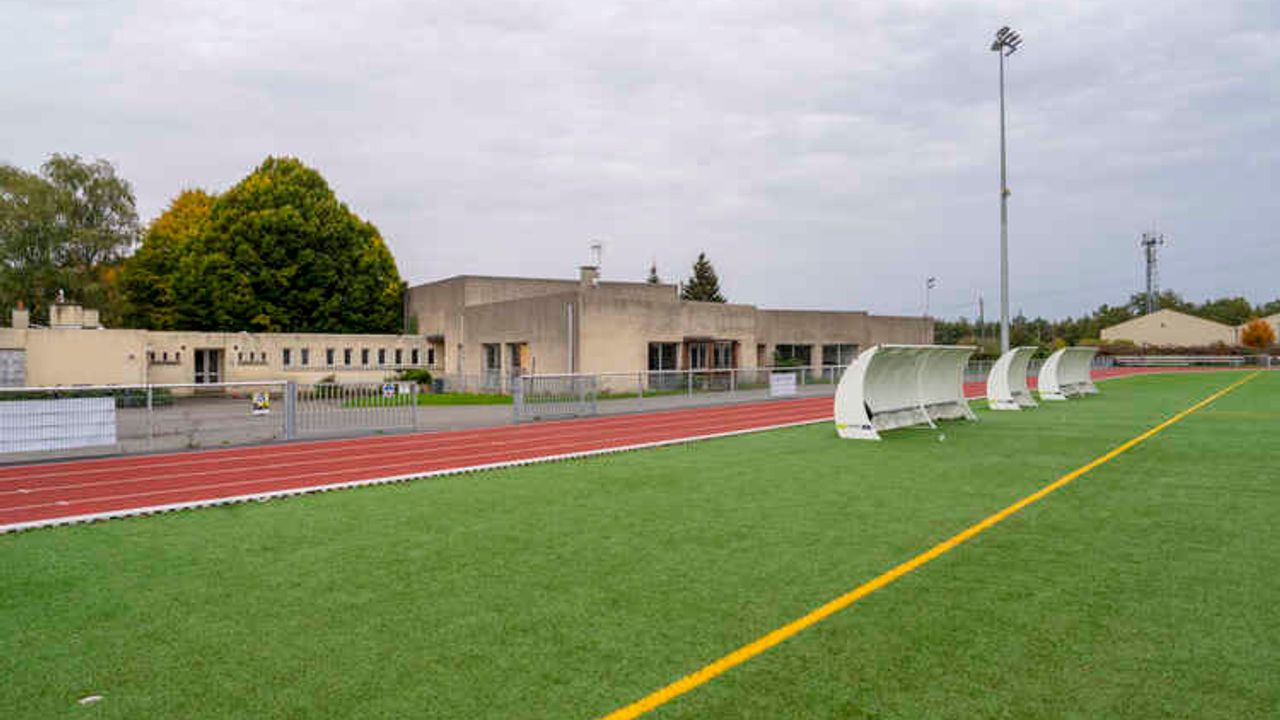 Terrain de sport en premier plan, et en arrière plan les locaux