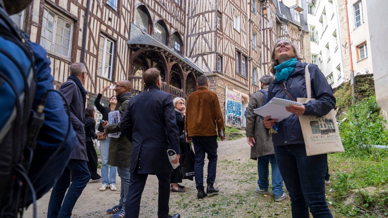 Une délégation d'élus devant des maisons à pans de bois datant du 17e siècle au centre de Rennes.