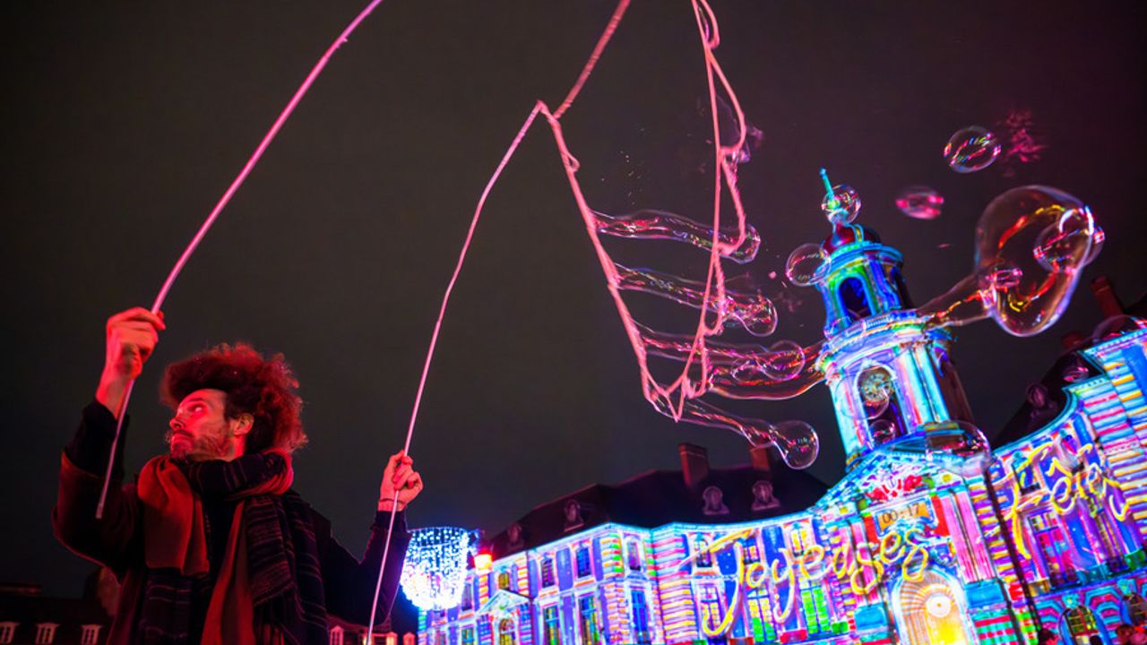 De nuit, un artiste crée de géantes bulles devant l'Hôtel de Ville illuminé