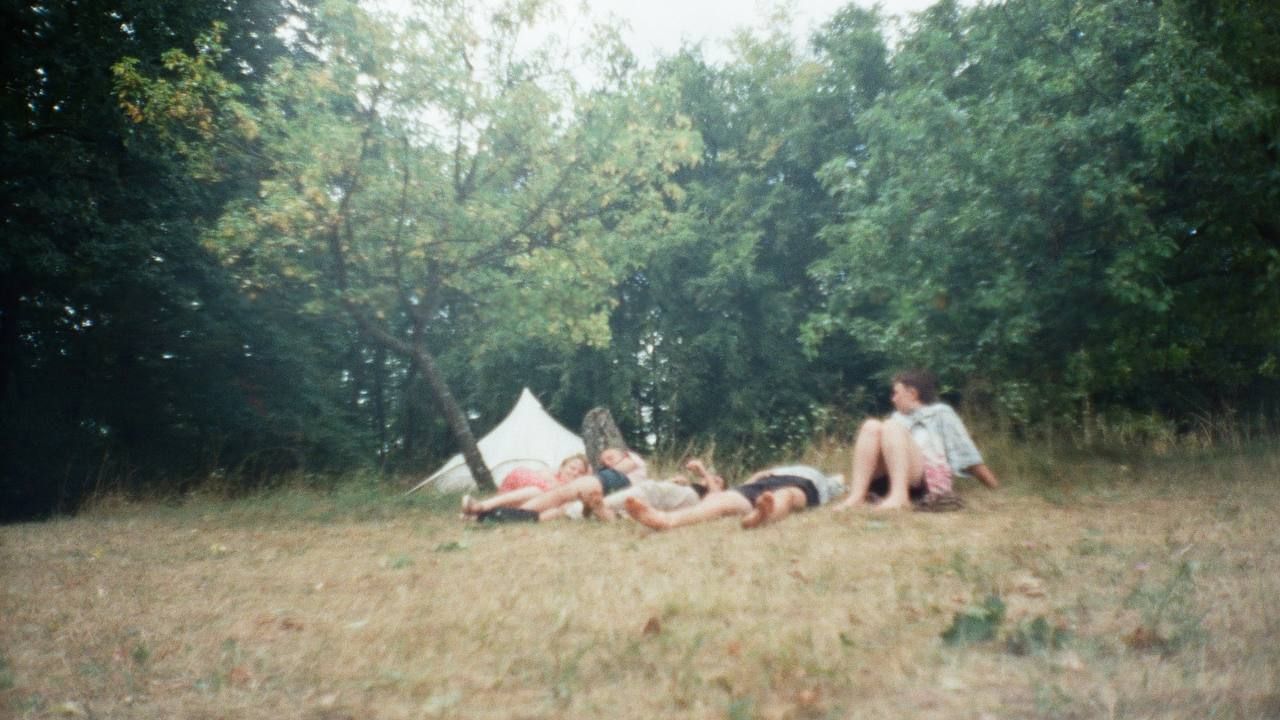 people lying down on the grass by the forest
