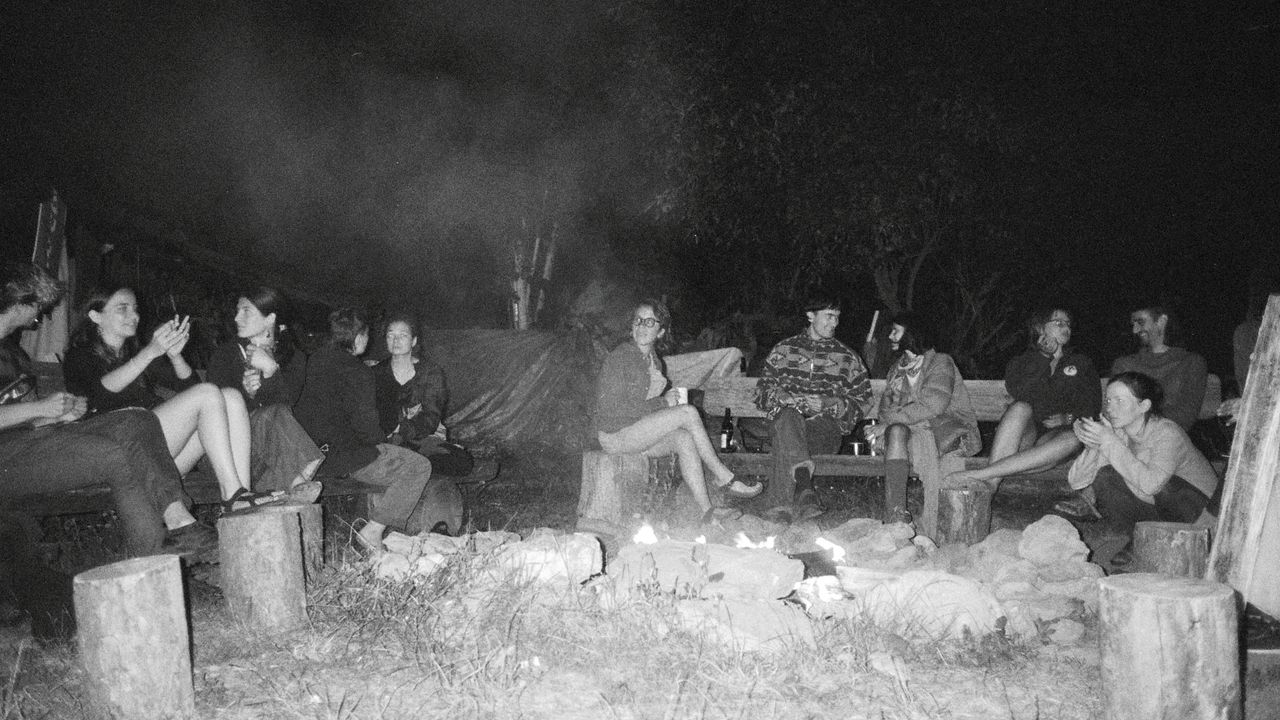 black and white picture of people sitting around the bonfire at night
