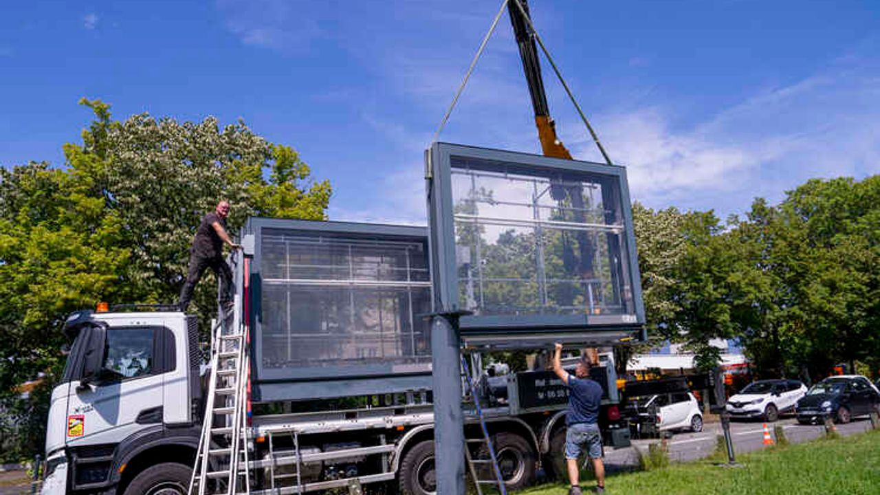 Enlèvement au premier plan d'un panneau d'affichage publicitaire de quatre mètres par trois mètres en bordure de rue dans la ville de Rennes, au second plan un camion avec plusieurs autres panneaux du même type enlevés sur sa remorque..