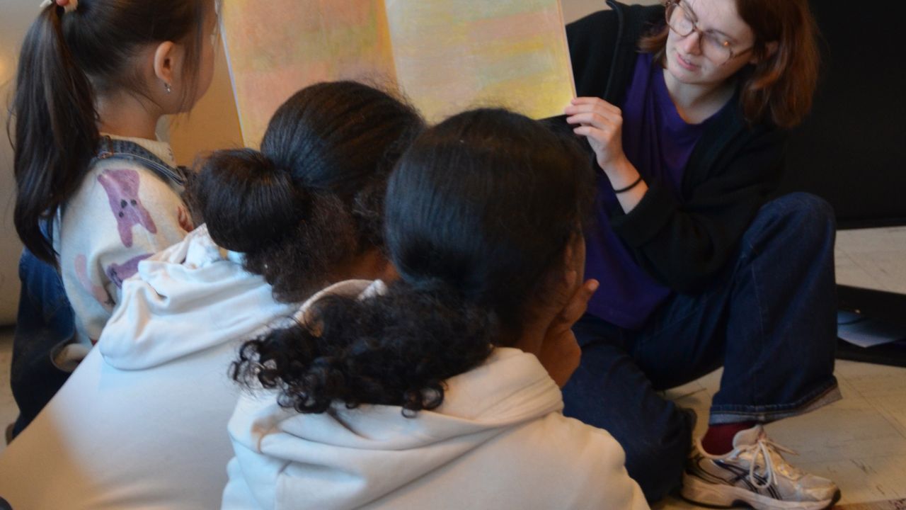 Margaux Janisset montre aux enfants ses carnets de dessins irridescents.