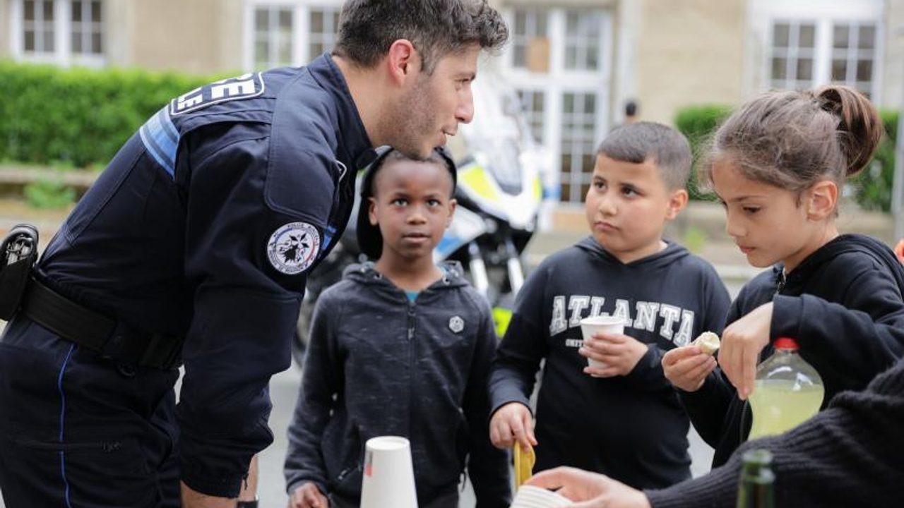 Un policier municipal échange avec trois jeunes autour d'un goûter.