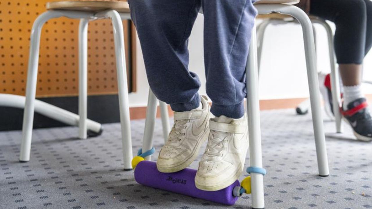 Un enfant assis utilise un rouleau en mousse au niveau des pieds