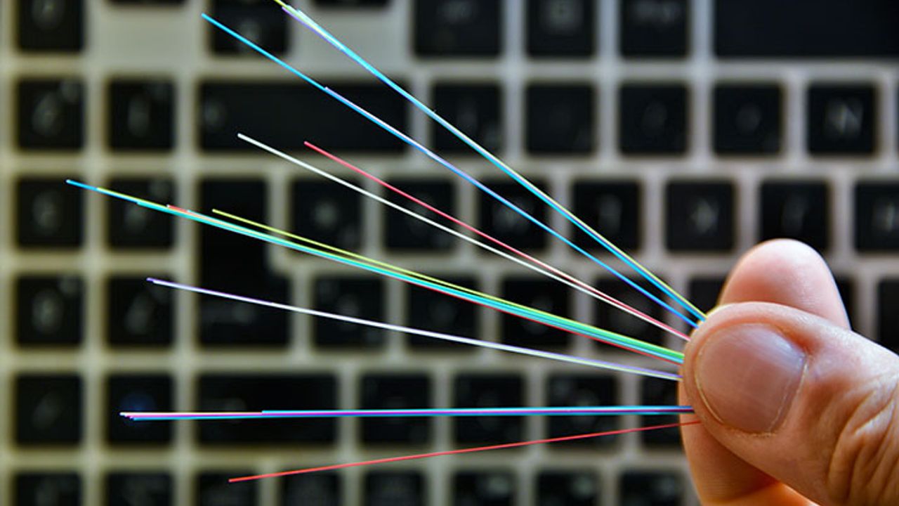 des fibres tenues par des doigts avec un clavier d'ordinateur en fond