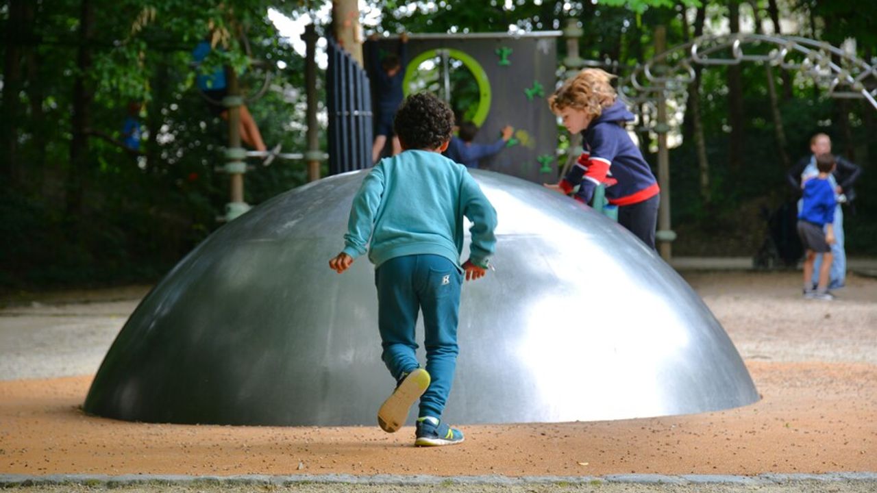 Un enfant s'élance vers une structure métallique à escalader.