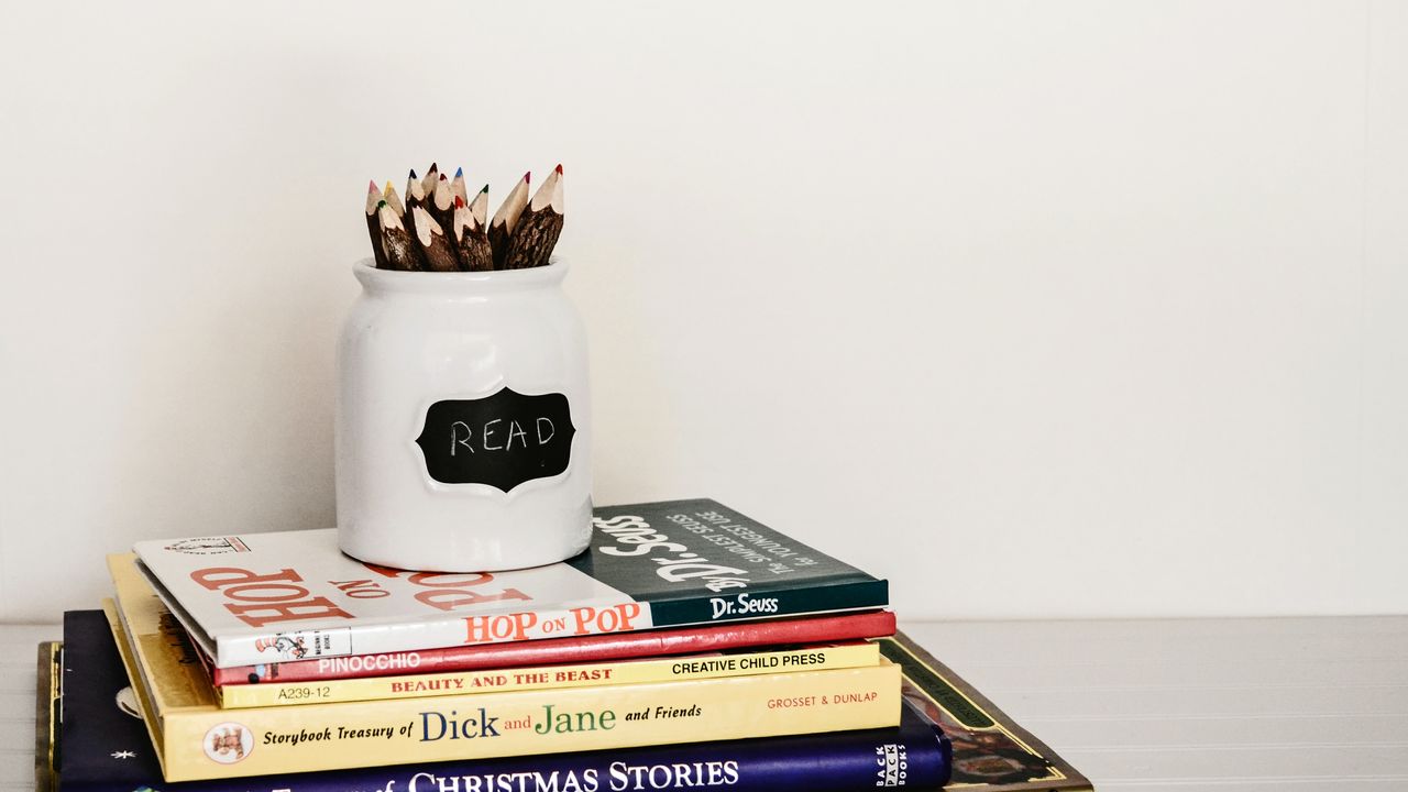 white ceramic pencil organizer on top of stack of books
